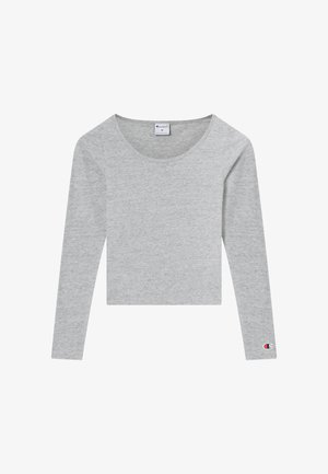 Camiseta gris de manga larga y corte corto, hecha de tela suave con cuello redondo, que presenta un pequeño parche de logo en la manga derecha.