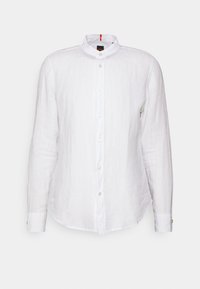 Camisa de lino blanca de manga larga con cuello alzado, cierre frontal con botones y un dobladillo ligeramente curvado. Presenta una textura sutil y detalles de costura.