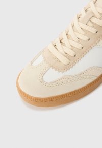 Baskets beiges avec une tige en cuir lisse, des accents en daim et une semelle en caoutchouc gomme. Présente un design en forme de scallop et des lacets plats.
