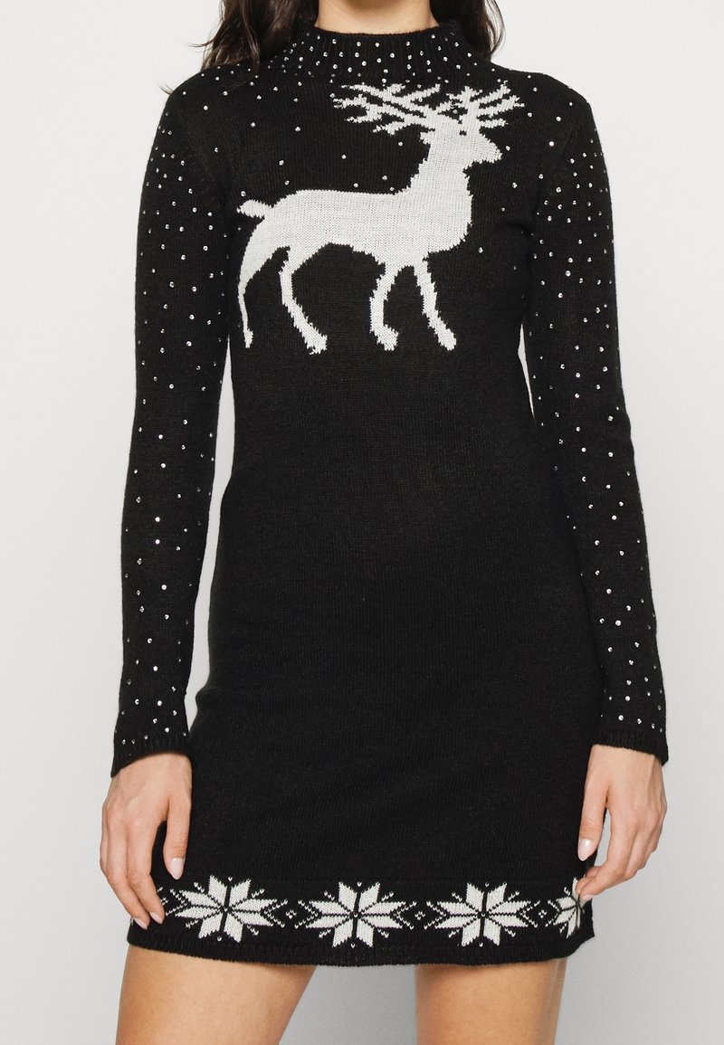 Svartstickad klänning med en vit ren-design, pärlprydnader på ärmarna och ett vitt snöflingemönster längs fållen.