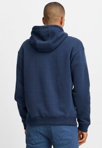 Felpa blu navy con cappuccio regolabile, polsini e orlo a costine. Texture morbida, vestibilità comoda e senza grafiche o motivi visibili.