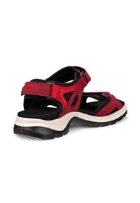 Punainen ja musta varvassandaali säädettävillä remmeillä, pehmustetulla pohjallisella ja karkealla mustavalkoisella ulkopohjalla.