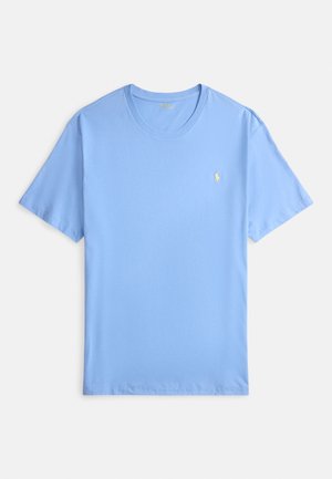 T-shirt de algodão azul claro com mangas curtas, decote redondo e um pequeno logótipo amarelo bordado no lado esquerdo do peito. Textura macia.
