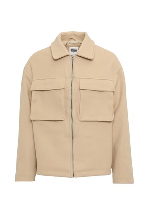 Veste zippée beige avec col, deux poches poitrine et coupe décontractée, fabriquée à partir d'un tissu doux et texturé.