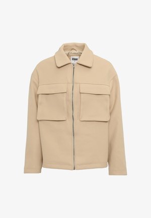 Chaqueta beige de cremallera con cuello, dos bolsillos en el pecho y un corte relajado, hecha de una tela suave y texturizada.