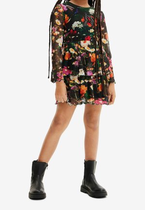 Long-sleeve floral dress with a pleated design, featuring a black background and colorful flowers. Paired with black leather ankle boots.