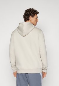 Beige Kapuzenpullover mit Kordelzug, gerippten Bündchen und Saum. Weiche Textur, lässige Passform und keine sichtbaren Logos oder Muster.