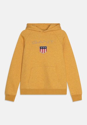 Mosterdgele sweatshirt met capuchon en voorzak, met het "GANT"-logo en een schildembleem met drie sterren en rode strepen.
