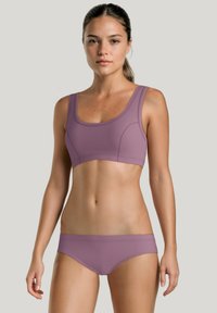 Ensemble deux pièces comprenant un soutien-gorge de sport lilas à encolure dégagée et un slip de bikini assorti. Tissu lisse et extensible avec des coutures minimales.