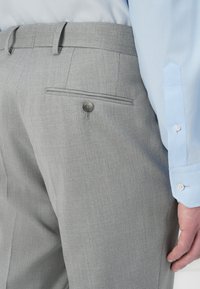Gray pinstriped trousers with a buttoned back pocket, paired with a light blue long-sleeve shirt. Smooth fabric, tailored fit visible.