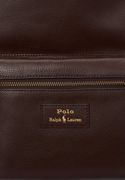 Dunkelbraunes, strukturiertes Leder mit einem horizontalen Messingreißverschluss über einem aufgenähten Polo Ralph Lauren Logo-Patch in goldener Schrift.