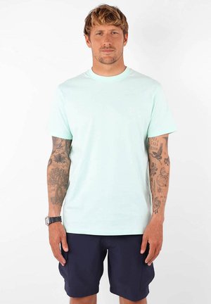 T-shirt en coton bleu clair avec des manches courtes, un col rond et un détail de logo subtil. Associé à un short bleu marine.