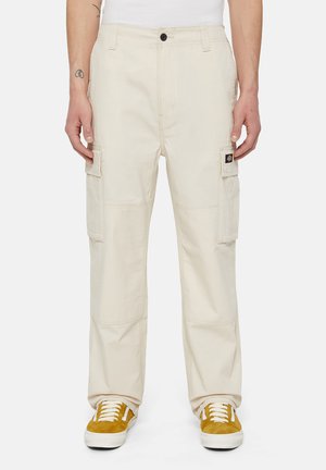 Beige cargobroeken van stevige stof, met zijzakken, een ontspannen pasvorm en een recht gesneden ontwerp. Gepaard met gele sneakers.