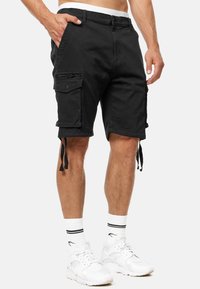 Shorts cargo noirs avec plusieurs poches, cordons de serrage réglables à l'ourlet et une poche zippée. Fabriqués en tissu durable avec une texture lisse.