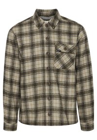 Chemise à carreaux en crème, marron et noir avec fermeture à boutons, col pointu et une poche poitrine. Tissu doux et texturé.
