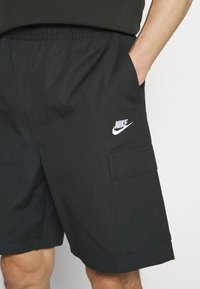 Svarta cargo-shorts med elastisk midja, med en sidoficka och vit Nike-logotyp fram. Tillverkade av lättviktsmaterial.
