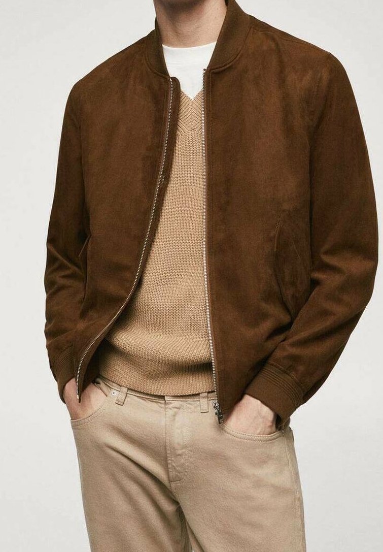 Chaqueta bomber de ante marrón con cuello y puños de punto, combinada con un suéter de punto beige y pantalones de color claro. Textura suave.
