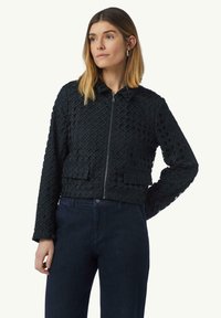 Zwarte gewatteerde cropped jack met een staande kraag, voorzien van een voorrits en twee opgestikte zakken. Draag het over donkere spijkerbroeken.