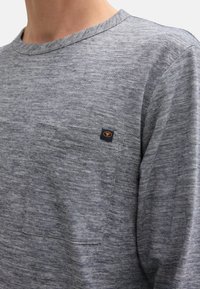 Graues Langarmshirt aus strukturiertem Stoff, mit einer Vorderfronttasche und einem kleinen Logotag auf der Brust.