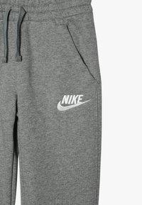 Pantaloni della tuta grigi in misto cotone con vita elastica, coulisse, tasche laterali e logo Nike bianco sulla coscia sinistra.