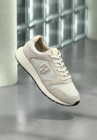 Αθλητικά παπούτσια σε ανοιχτό μπεζ χρώμα με υφές από δίχτυ και σουέτ. Διαθέτουν επενδυμένο γιακά, δέσιμο με κορδόνια μπροστά και μαύρη λαστιχένια σόλα με λεπτομέρεια λογότυπου.