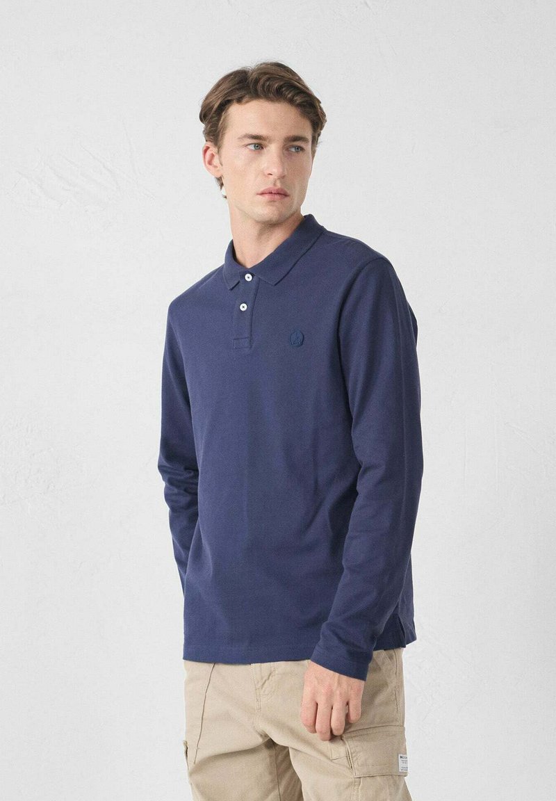 Polo a maniche lunghe di colore blu navy realizzato in cotone, con colletto, patta con tre bottoni e un piccolo logo sul petto.