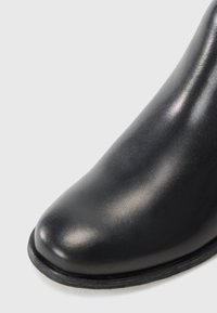 Svart skinn ankelstøvlett med avrundet tå, glatt overflate og flat gummisåle. Sømløst design for et strømlinjeformet utseende.