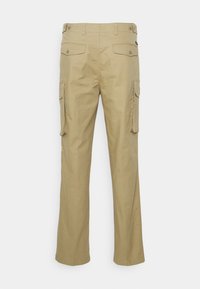Pantalon cargo beige en coton avec une coupe droit, doté de deux poches latérales et deux poches arrière, toutes fermées par des boutons.
