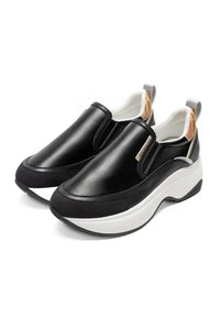 Svarta slip-on skor med en slät läderöverdel, kontrasterande vit sula, vadderad krage och en subtil tan färgnyans vid hälen.