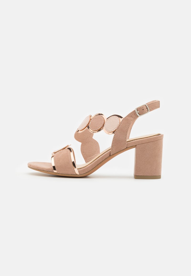 Sandales à talons en daim nude avec un détail circulaire sur la lanière, design à bout ouvert et un talon carré. Sangle de cheville ajustable incluse.