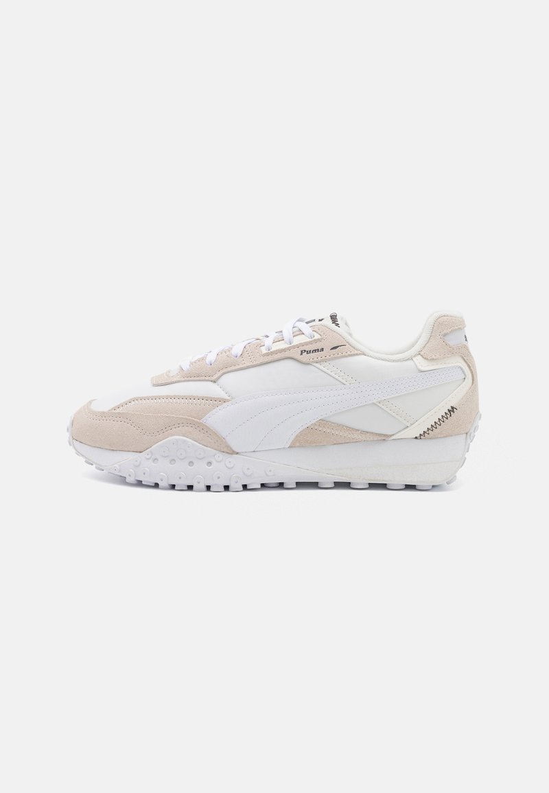 Beige og hvite sneakers med overdel i semsket skinn, teksturerte detaljer, snøring og gummisåle med sirkulære mønstre.