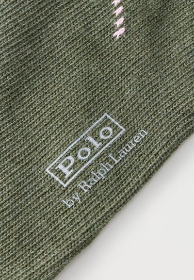 Roheline kootud kangas, mille serva lähedal on valge "Polo by Ralph Lauren" logo tikitud ning selle kohal väike roosa õmblusdetail.