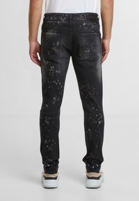 Czarne dżinsy o slim fit, z wyblakłym wykończeniem i rozpryskami. Standardowy design z pięcioma kieszeniami i z pętlami na pasek.