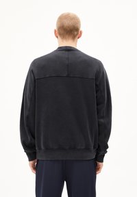 Black sweatshirt made from textured fabric, featuring a crew neck, loose fit, and visible stitching details on the back and sleeves.