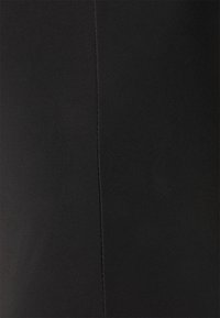 Gros plan sur un tissu noir lisse avec une couture verticale au centre.