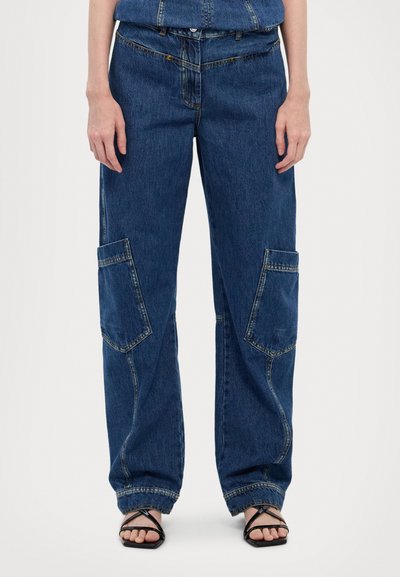 Pantalons cargo en denim bleu avec une coupe ample, dotés de grandes poches, d'une taille à cordon de serrage et de coutures contrastantes. Texture lisse avec un design classique.