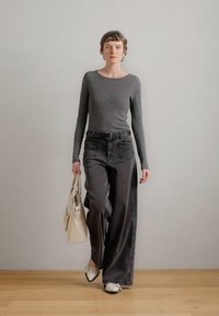 Γκρι ριμπέν μακρυμάνικο μπλουζάκι συνδυασμένο με φαρδιά σκούρα γκρι τζιν παντελόνια, ασημένια παπούτσια και κρεμ τσάντα. Μινιμαλιστικός σχεδιασμός, μαλακές υφές.