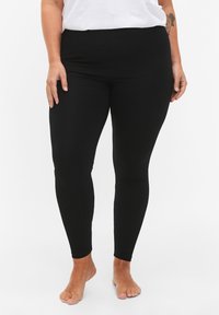Black leggings made from stretchy fabric, featuring a high waist, fitted design, and smooth texture. No visible patterns or hardware.