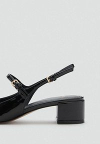 Černé lakované sandály na blokovém podpatku, s nastavitelným páskem kolem kotníku a zlatými sponami. Hladký povrch, elegantní design.