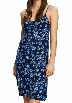 Un vestido de verano navy blue con estampado floral, tirantes ajustables, parte delantera fruncida y un detalle de lazo. Presenta patrones de flores en azul y verde por toda la prenda.