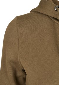 Hnědá fleecová mikina s texturovaným povrchem a kapucí na šňůrku. Obsahuje detailní pohled na ramenní šev a pleteninu látky.