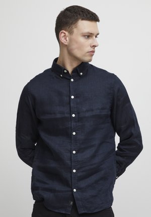 Marineblauwe button-up shirt van lichtgewicht stof, met een klassieke kraag, lange mouwen en witte knopen aan de voorkant.