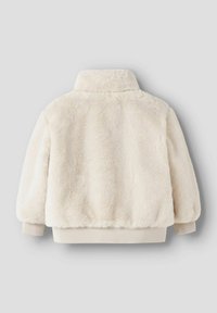 Valge kunstkarusnahast jakk kõrge krae ja soonikkoelusega varrukaotstega. Pehme tekstuur, lühendatud lõige ja paelaga ääristatud alumine serv tihedaks istuvuseks.