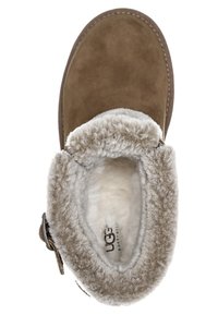 Bruine suède enkellaarzen met een zachte, crèmekleurige schapenvachtvoering en een decoratieve riem aan de zijkant. Rond neusontwerp.