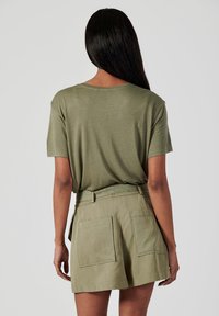 T-shirt vert olive avec une coupe décontractée, des manches courtes et un col rond, associée à un short taille haute assorti avec deux poches arrière.
