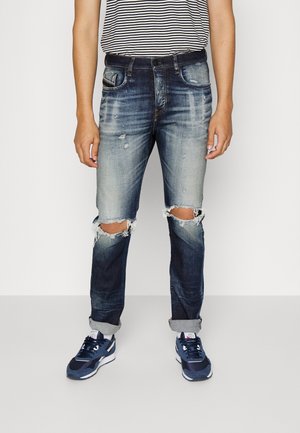 Jeans aus Denim in Blauverlauf, mit einem distressed Design und gerissenen Knien, gerader Passform und hochgekrempelten Säumen. Kombiniert mit navy Sneakern.