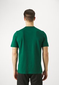 Camiseta de algodón verde con cuello redondo y mangas cortas. Diseño simple, tejido ligero y corte relajado. Sin patrones ni logos visibles.