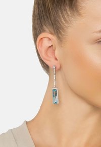 Rectangular blue earrings with a clear stone accent, featuring a sleek design, silver-tone metal, and a shimmering textured finish.