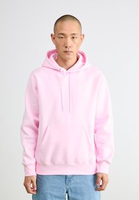 Rosa hettegensere laget av myk stoff, med en frontlomme og en hvit logo på brystet. Lange ermer med ribbede mansjetter.