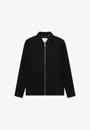 Musta vetoketjullinen takki, jossa on pystykaulus, kaksi etutaskua ja sileä pinta. Sisältää keskivetoketjun ja hillittyä brändäystä sisäpuolella.